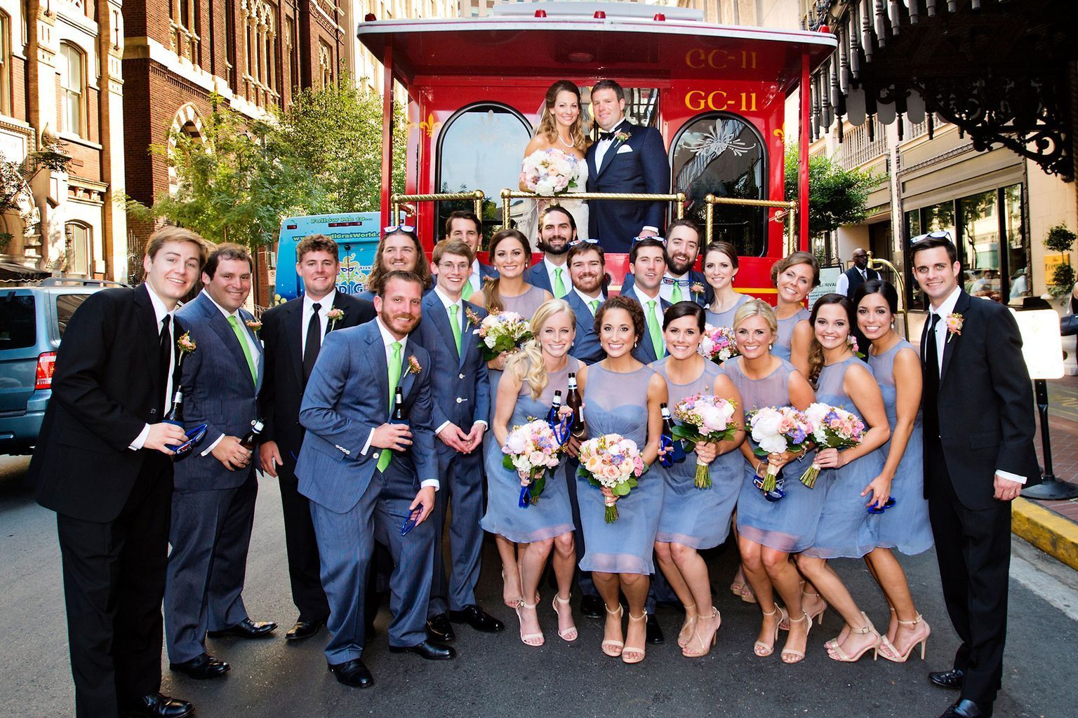 A group of people posing for a picture in front of a trolley