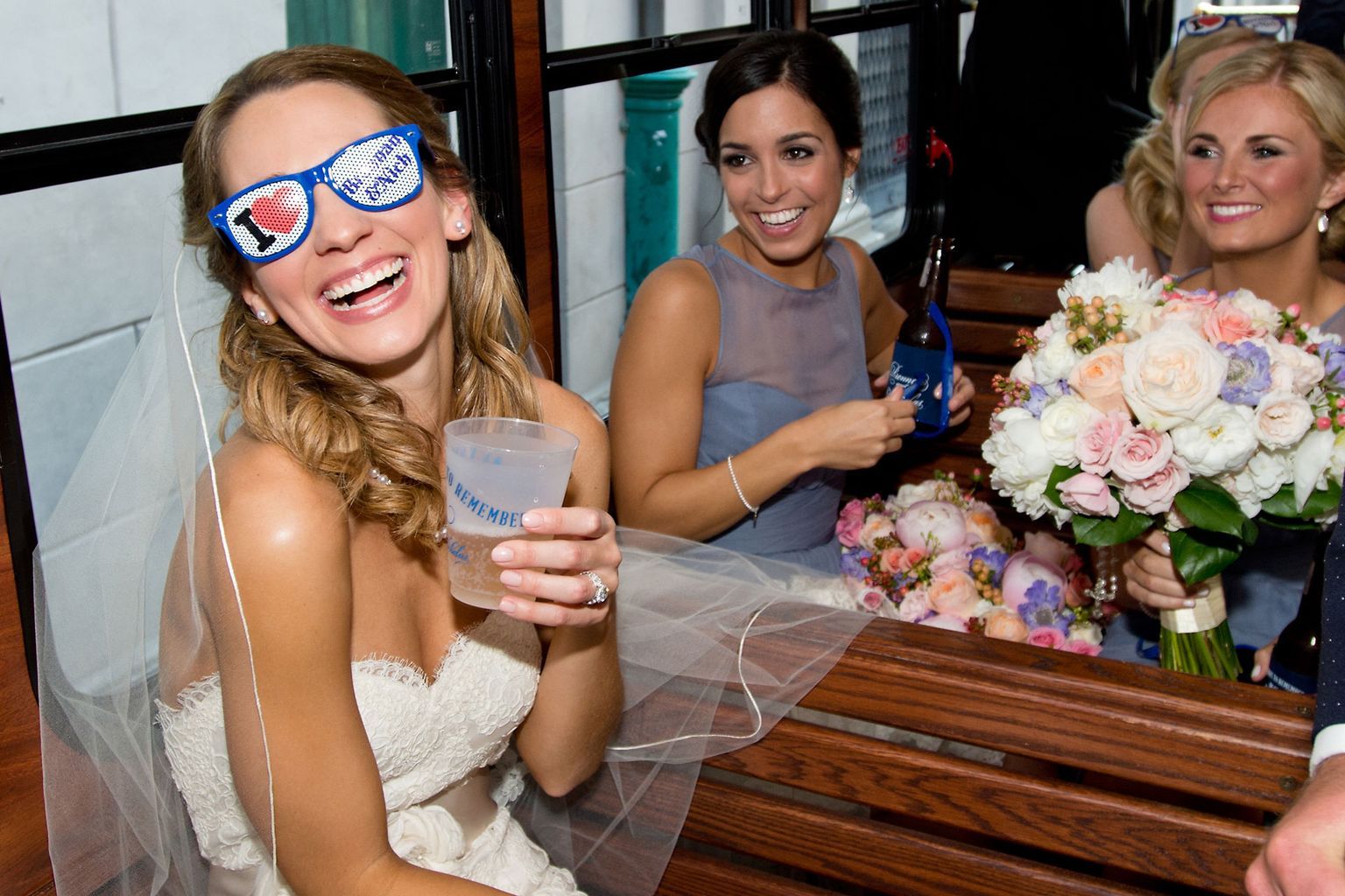 The bride is wearing sunglasses and holding a drink