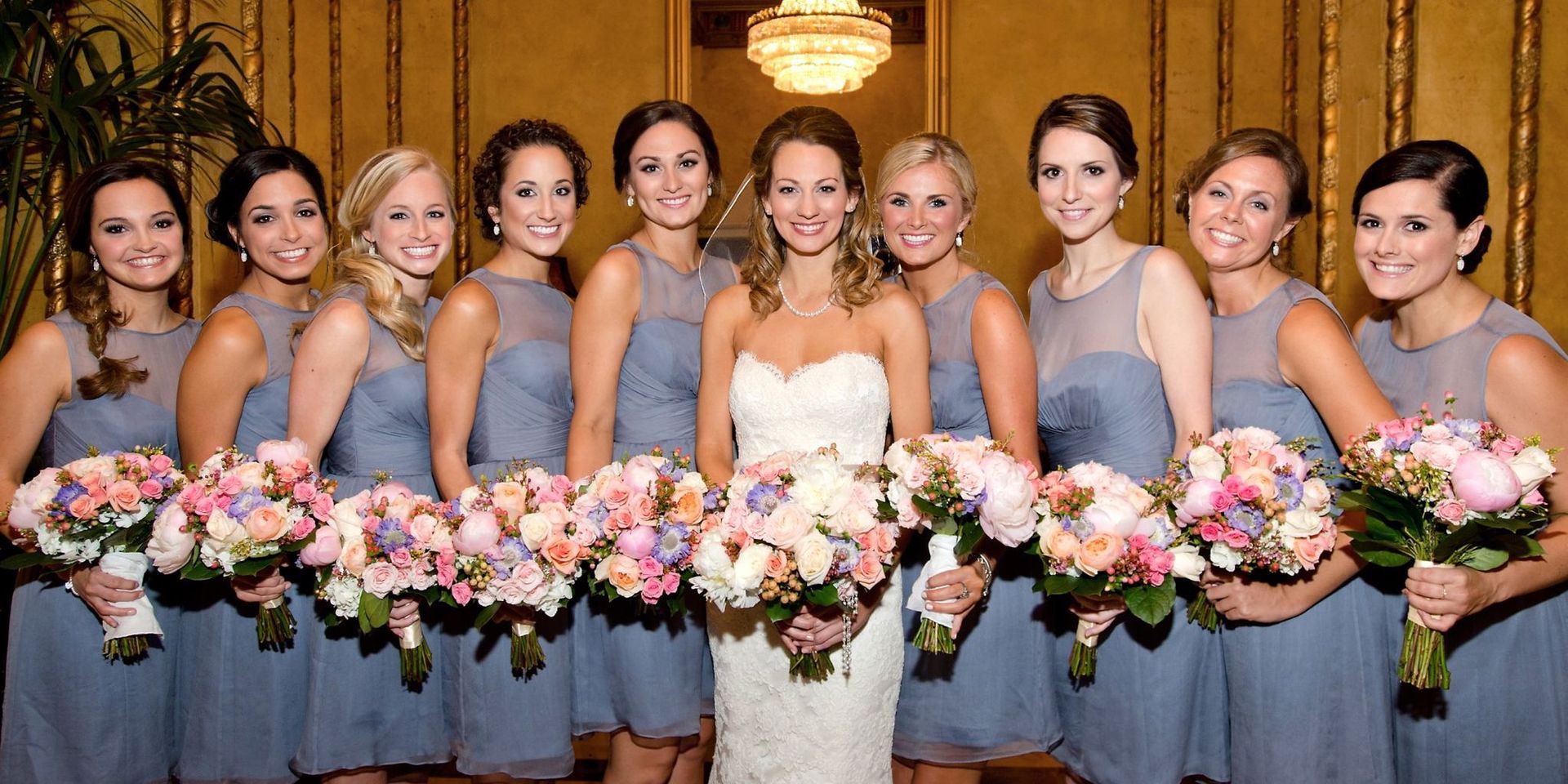 A bride and her bridesmaids are posing for a picture holding bouquets of flowers.