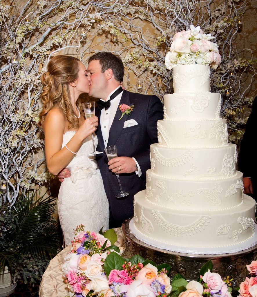 A bride and groom kissing in front of a wedding cake