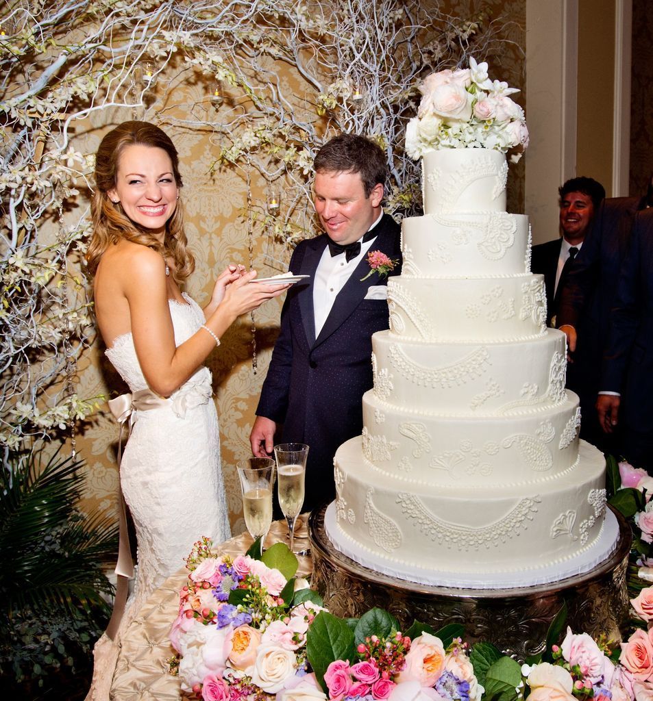 A bride and groom are cutting their wedding cake