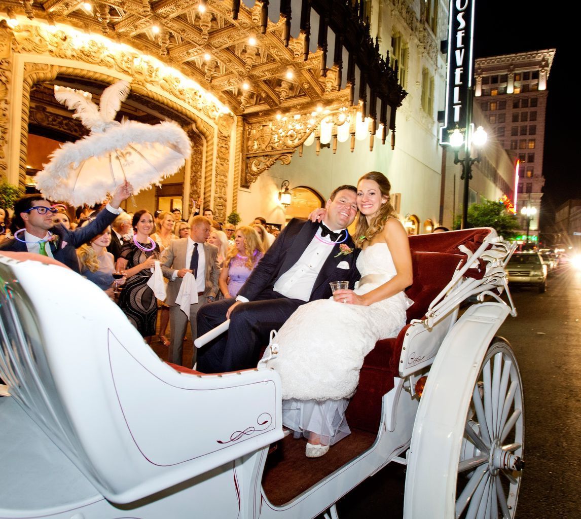 A bride and groom are riding in a horse drawn carriage