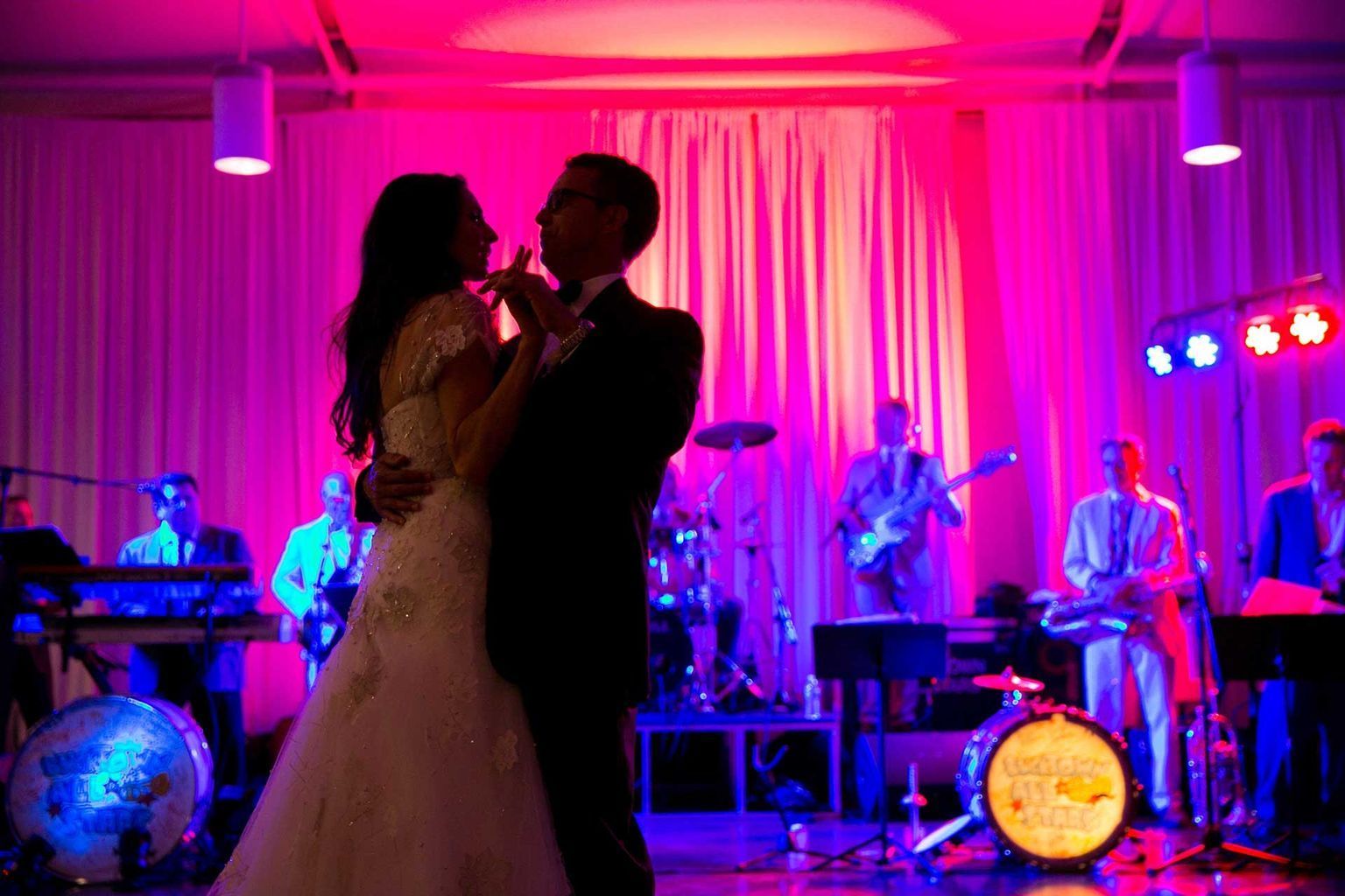 A bride and groom are dancing on a stage in front of a band.
