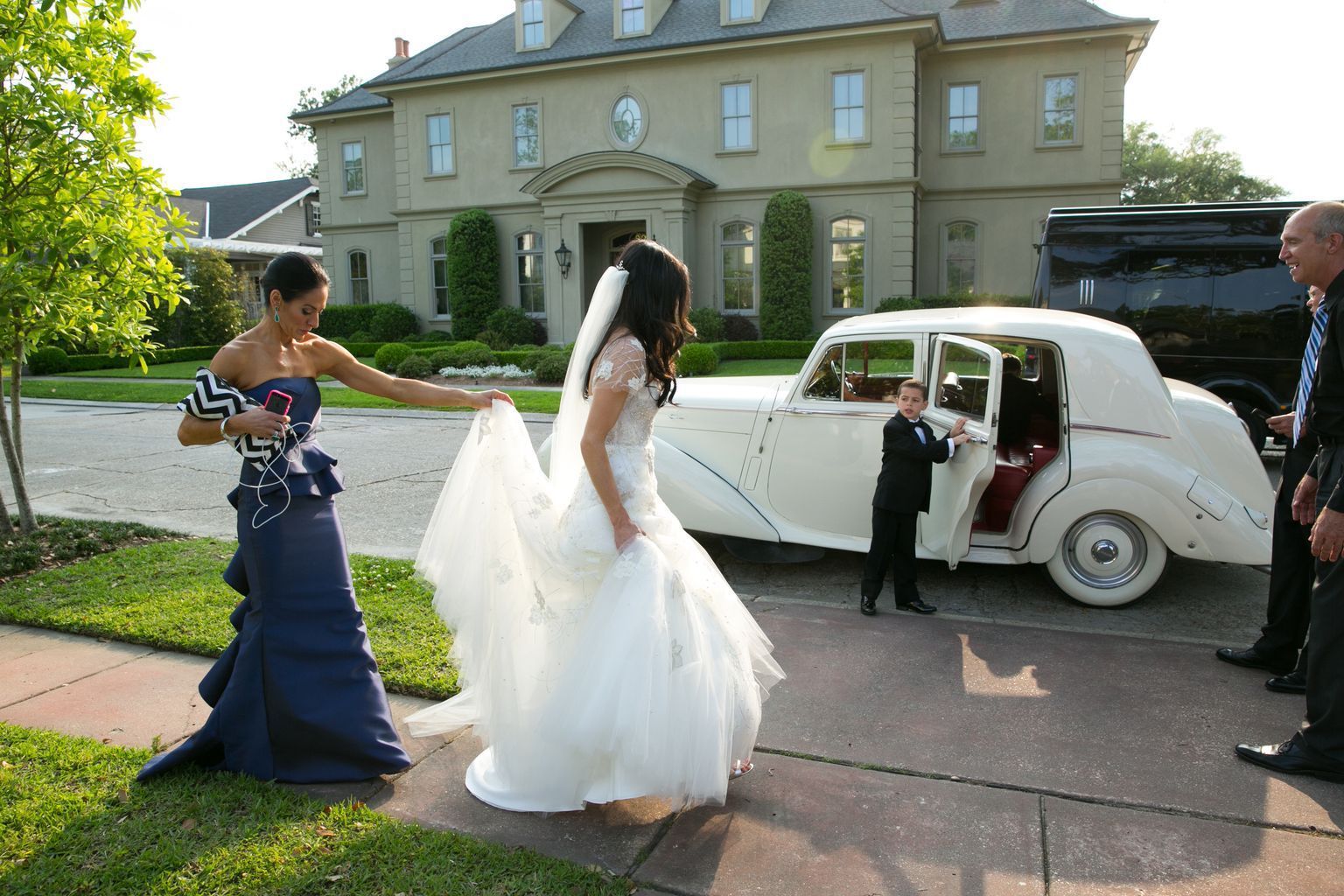 A bride and groom are getting out of a white car