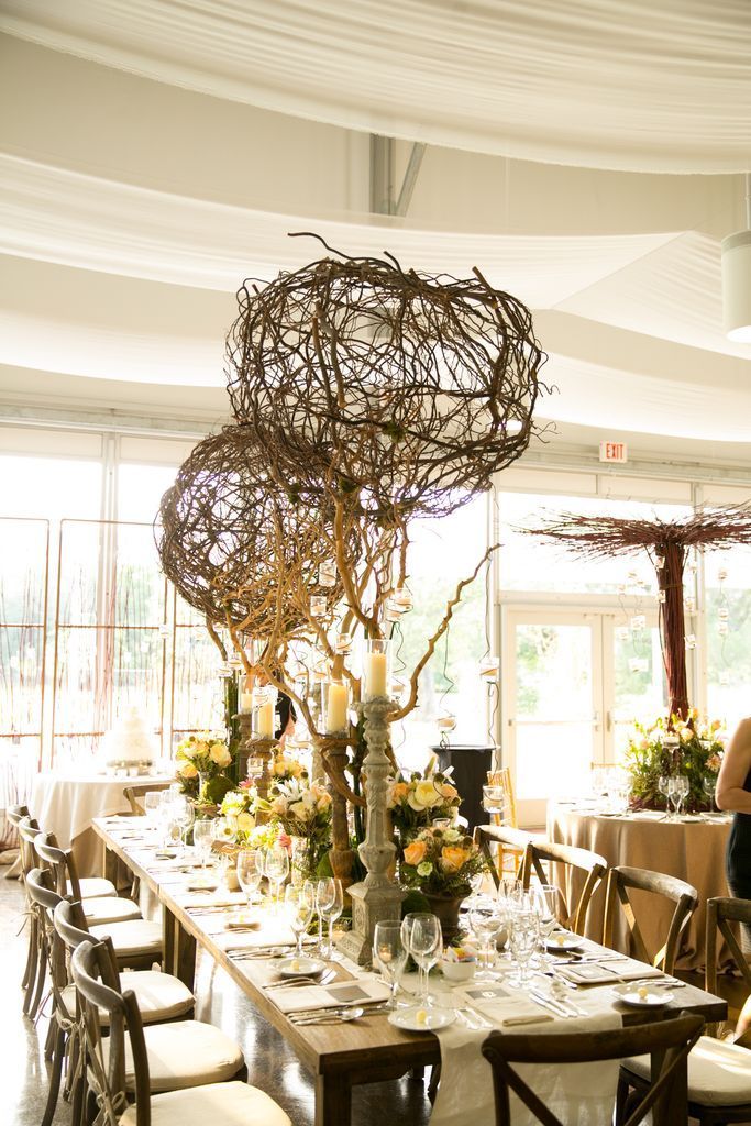 A long table set for a wedding reception with flowers and candles on it.