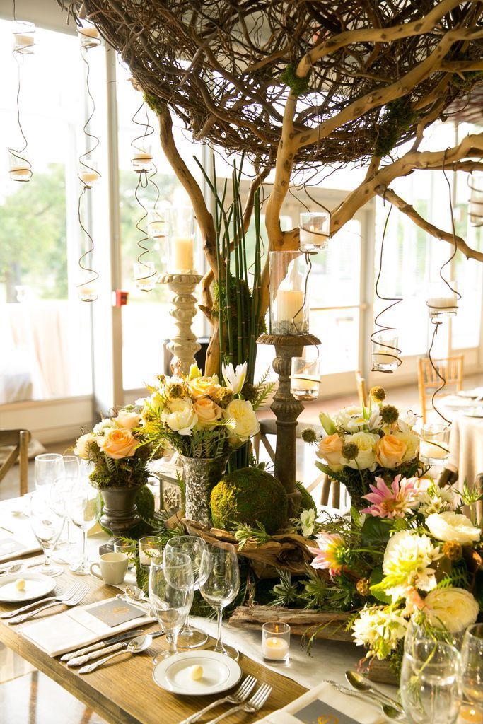 A table set for a wedding reception with flowers and candles on it.