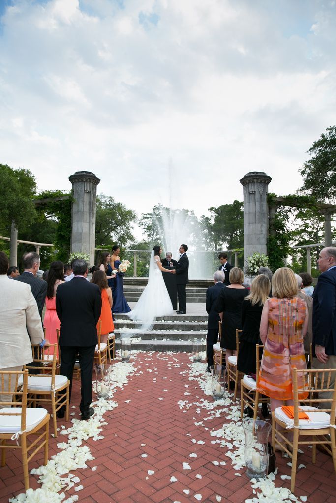 A bride and groom are getting married in front of a fountain
