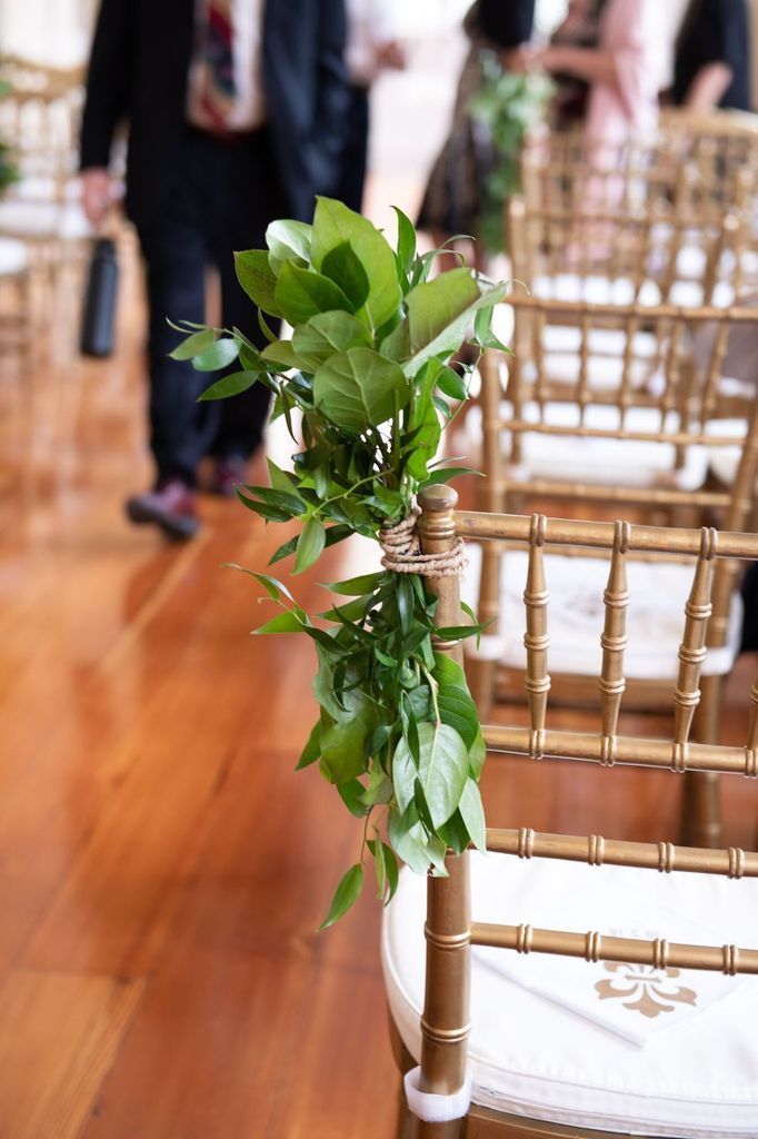 A row of chairs with green leaves tied to them.