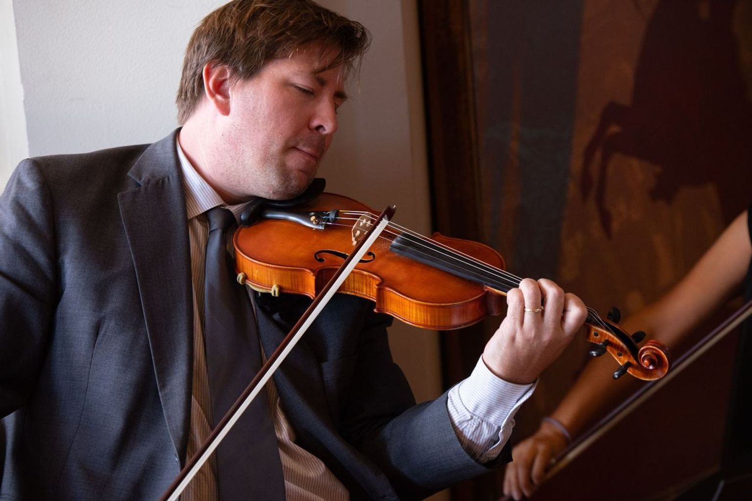 A man in a suit and tie is playing a violin