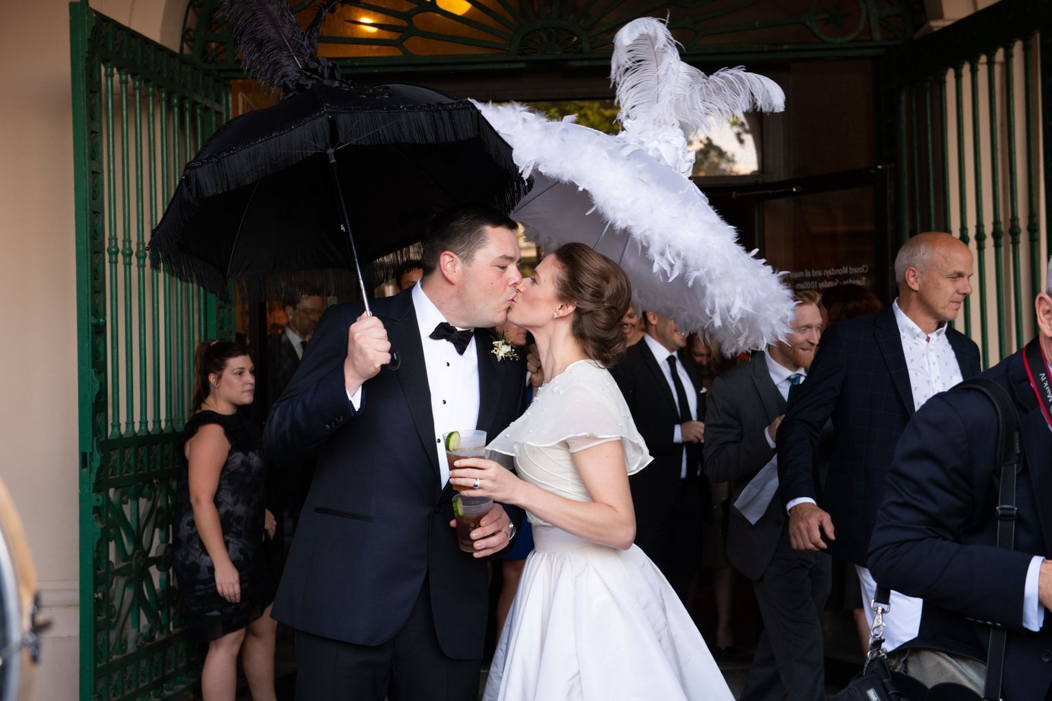 A bride and groom are kissing under an umbrella.