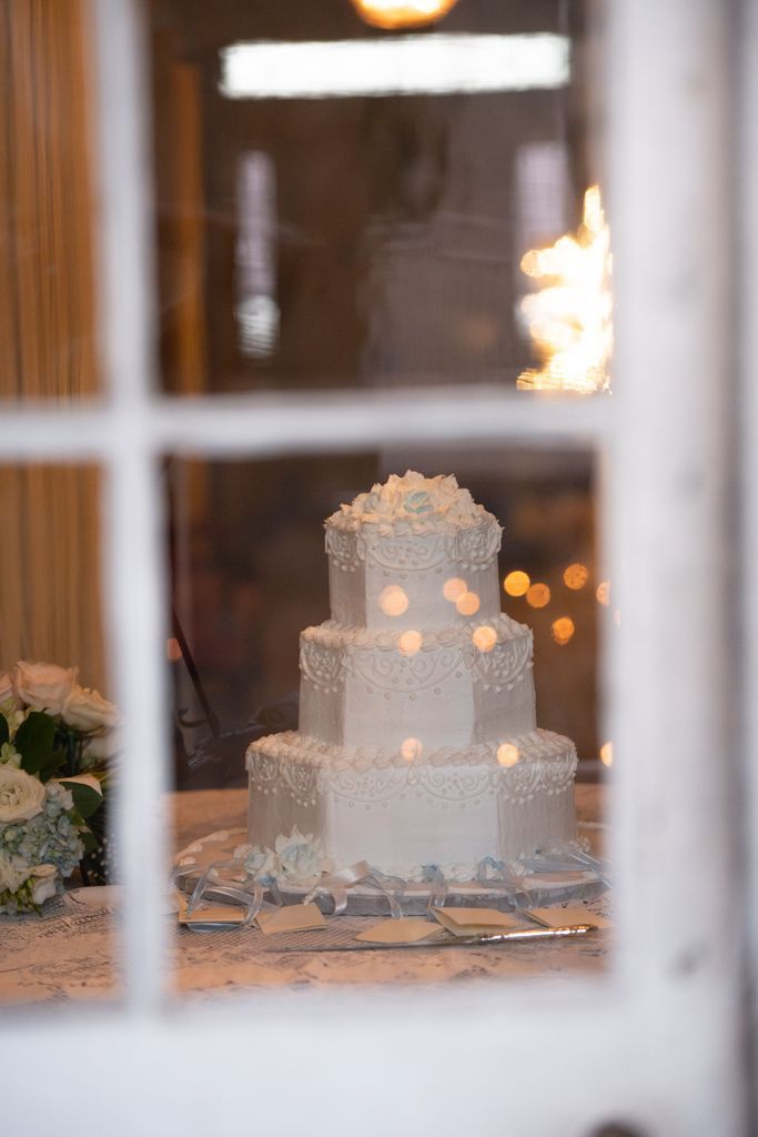 A wedding cake is sitting on a table in front of a window.