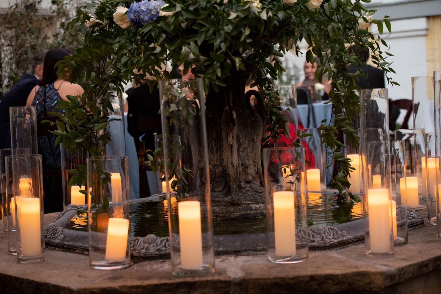 A group of candles are sitting on a table in front of a tree.