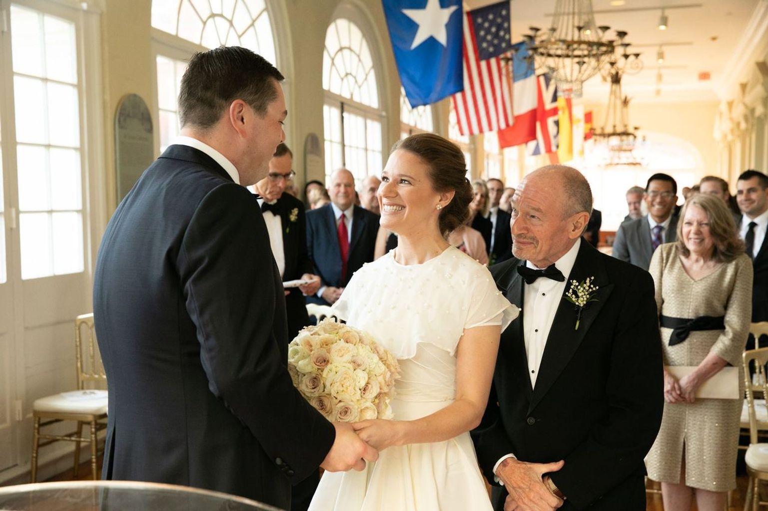 A bride and groom are holding hands during their wedding ceremony.