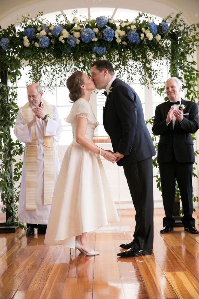 A bride and groom are kissing during their wedding ceremony.