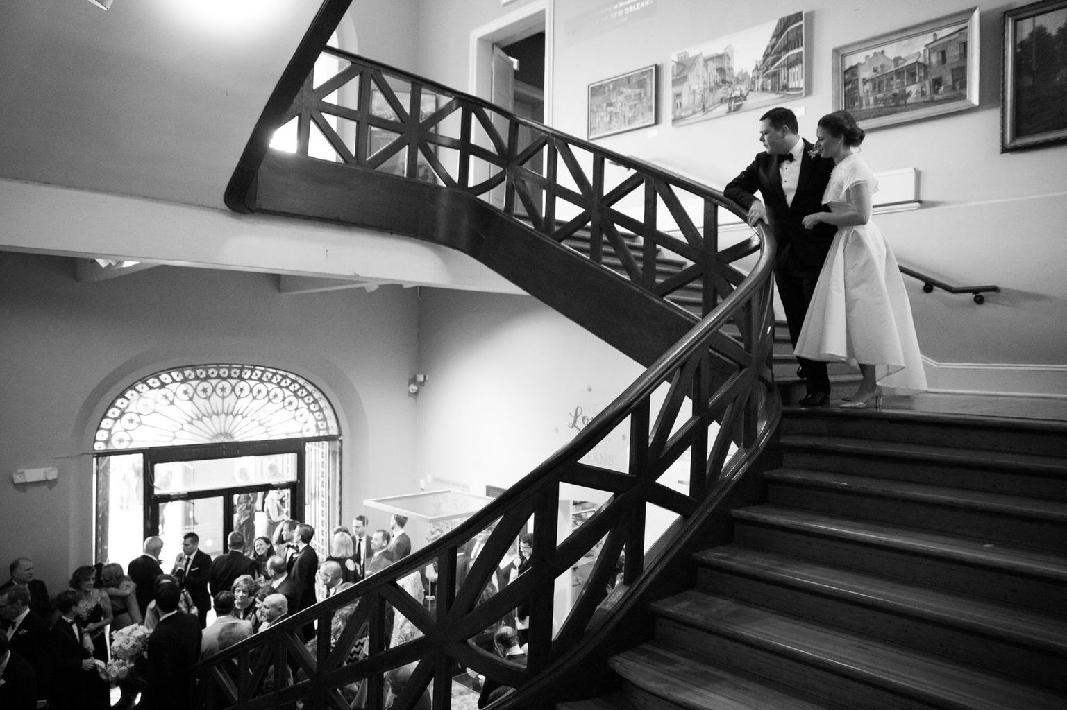 A black and white photo of a bride and groom walking down a set of stairs.