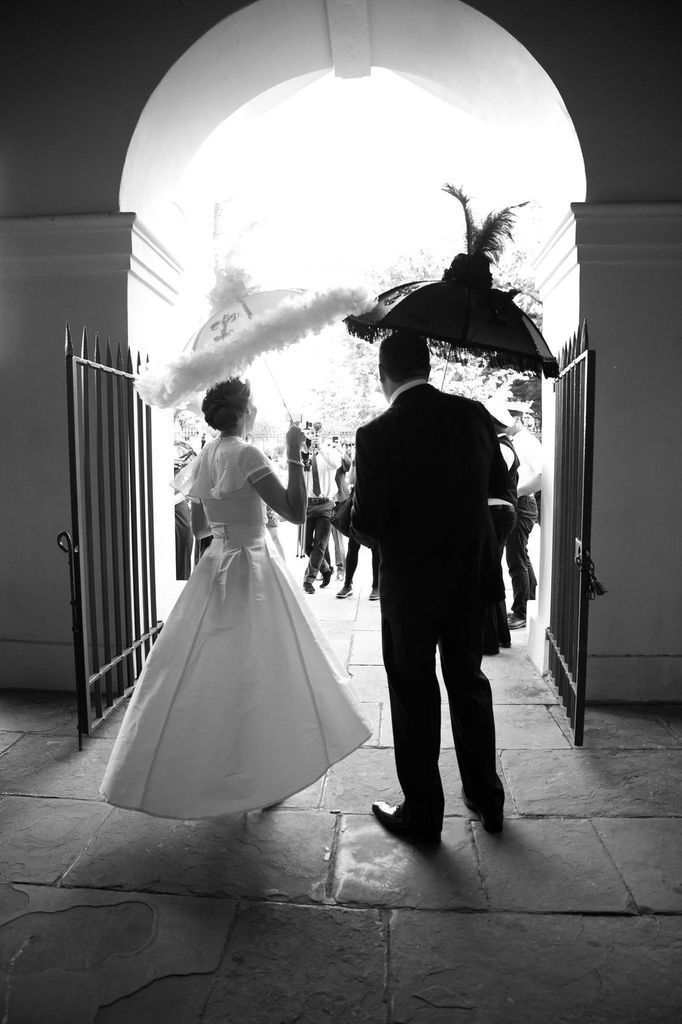 A black and white photo of a bride and groom walking through a doorway.