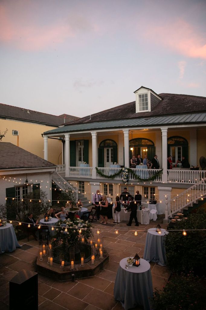 A group of people are sitting at tables in front of a large house.