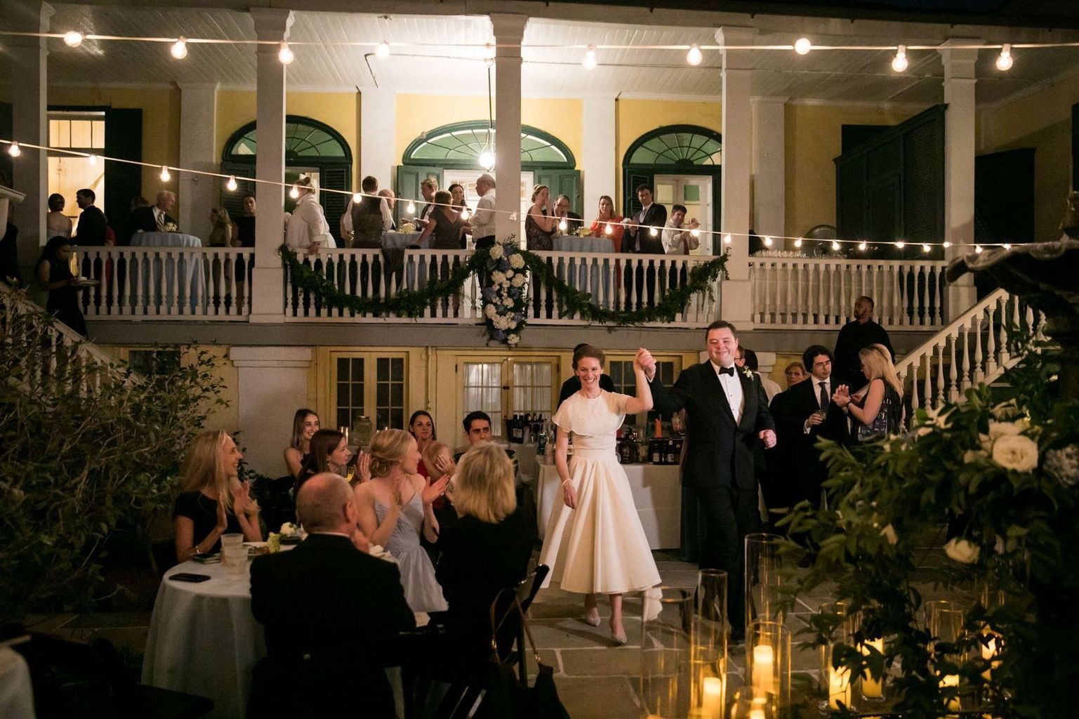 A bride and groom are walking through a crowd of people at a wedding reception.