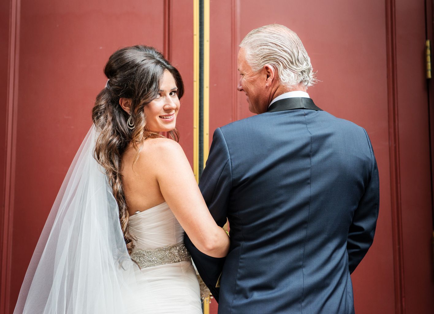 A bride and groom are standing next to each other in front of a red door.