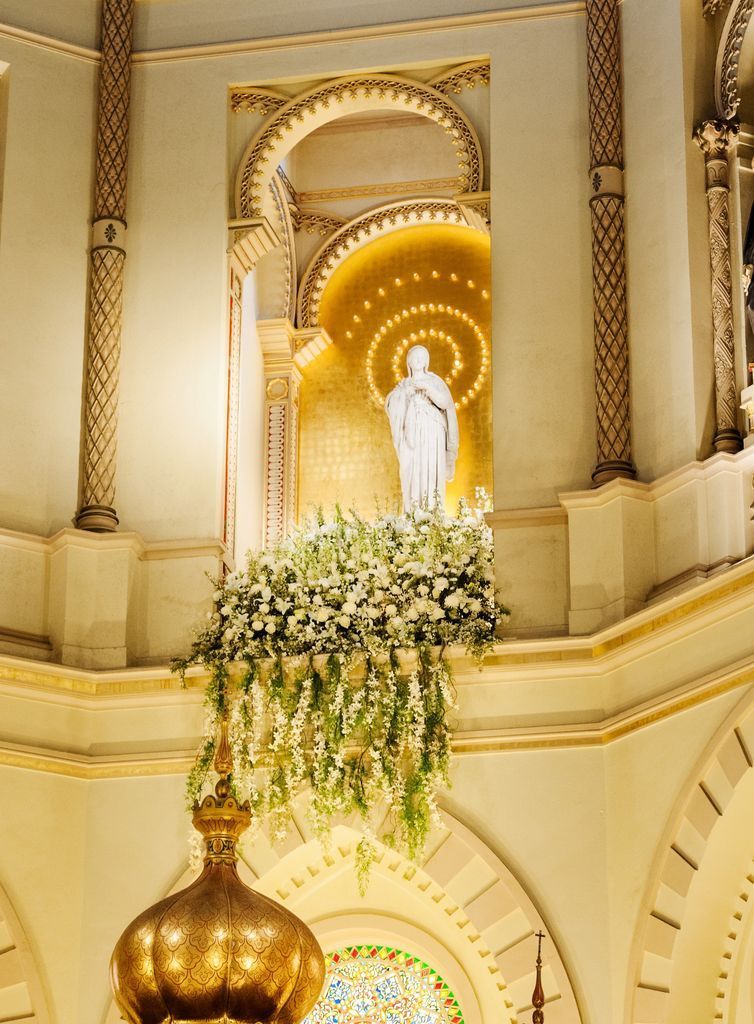 A statue of jesus is surrounded by flowers in a church.