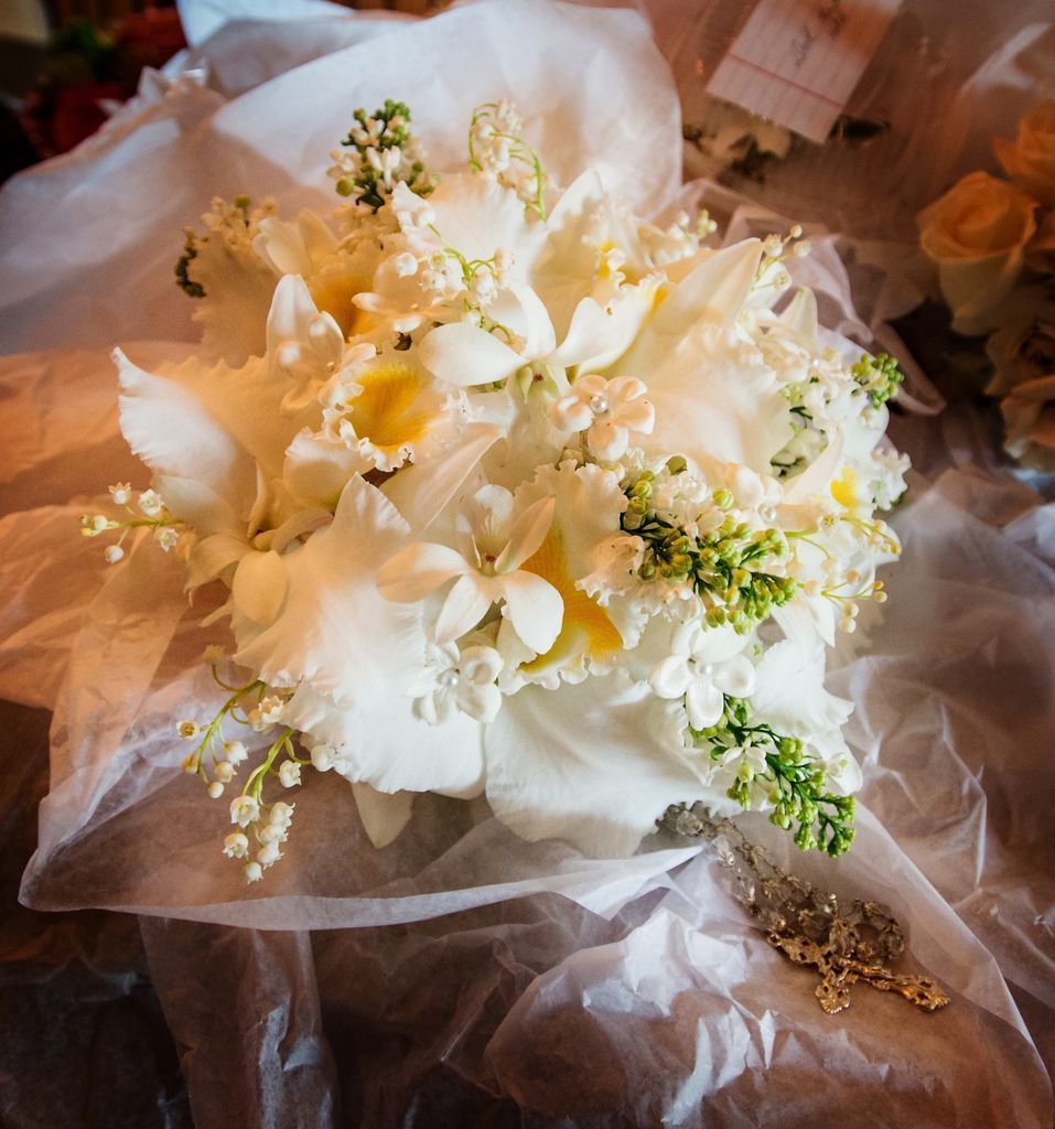 A bouquet of white flowers is wrapped in plastic and sitting on a table.