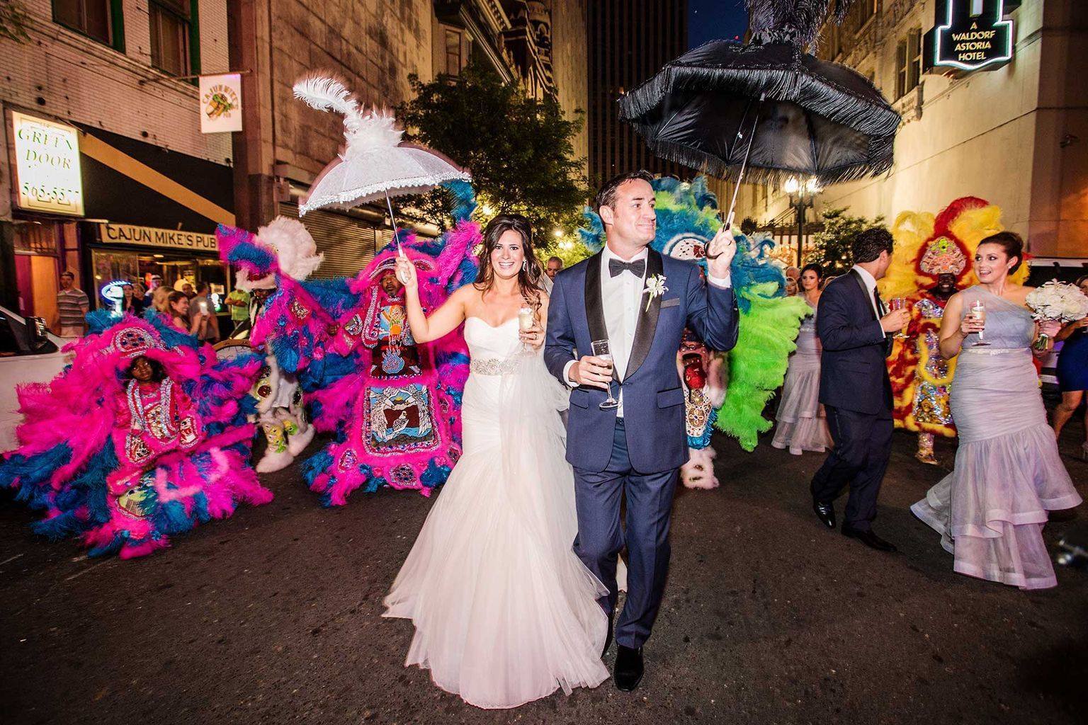 A bride and groom are walking down the street in a parade.