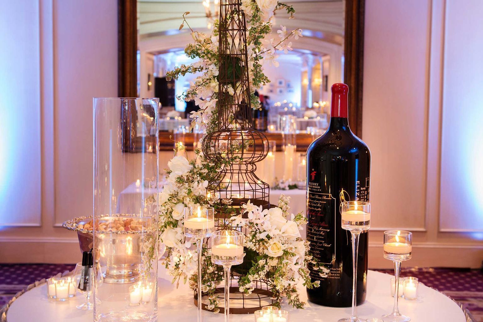 A bottle of wine is sitting on a table with candles and flowers.