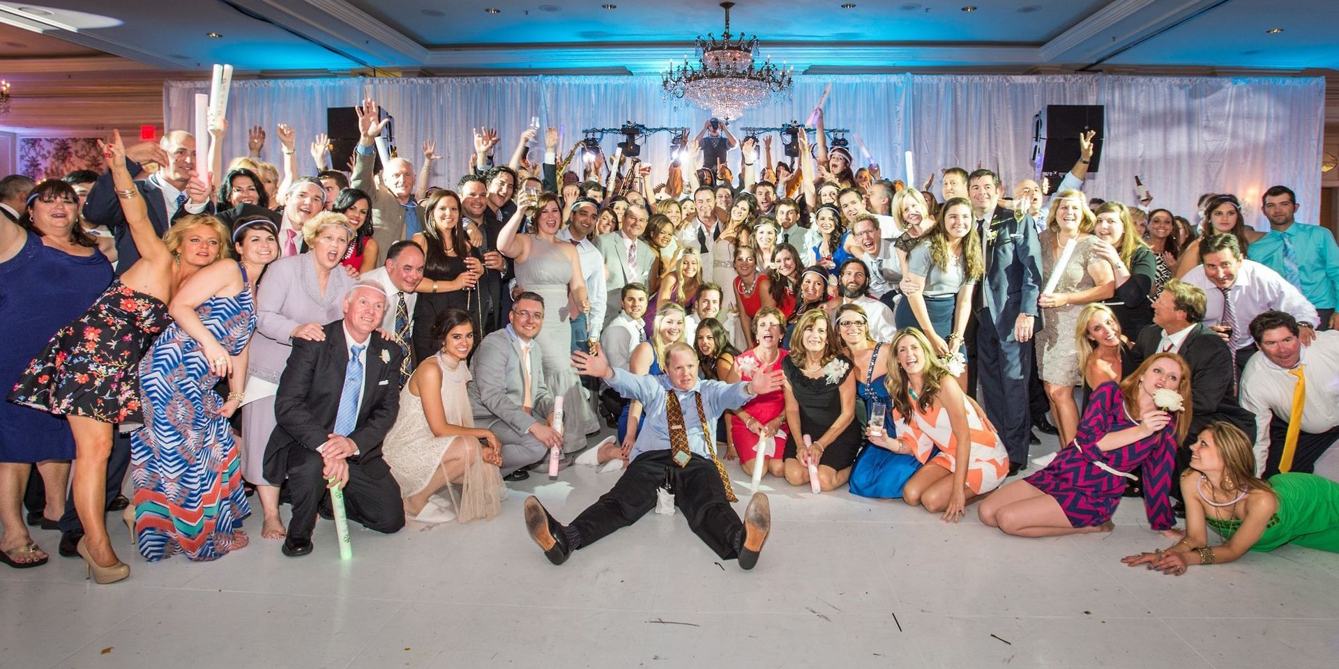 A large group of people are posing for a picture at a wedding reception.