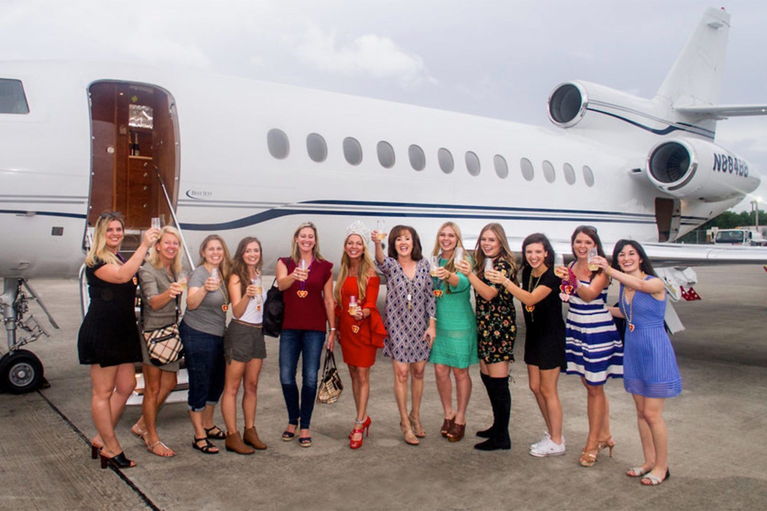 A group of women are standing in front of a private jet.