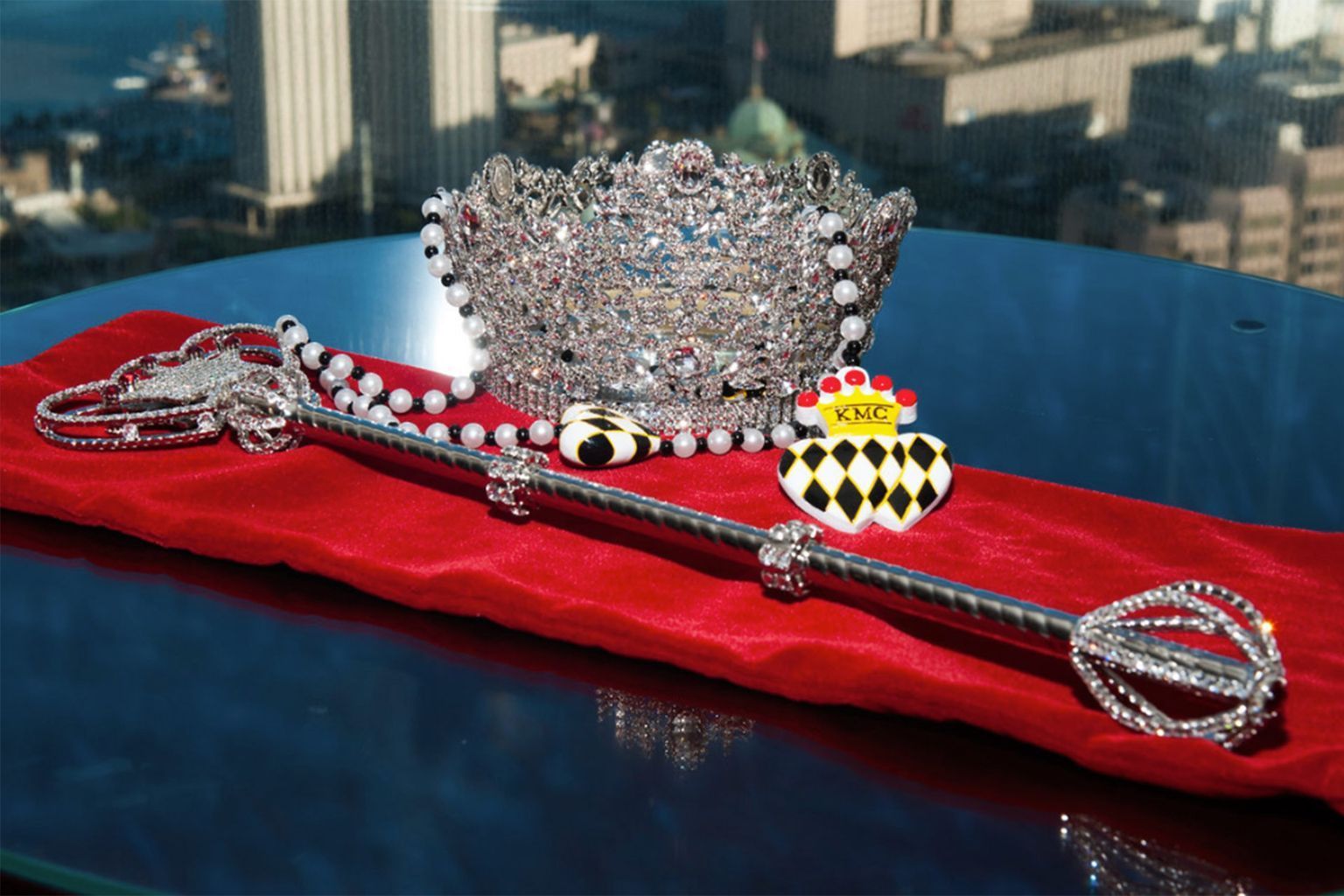A crown and scepter are sitting on a red cloth on a table.