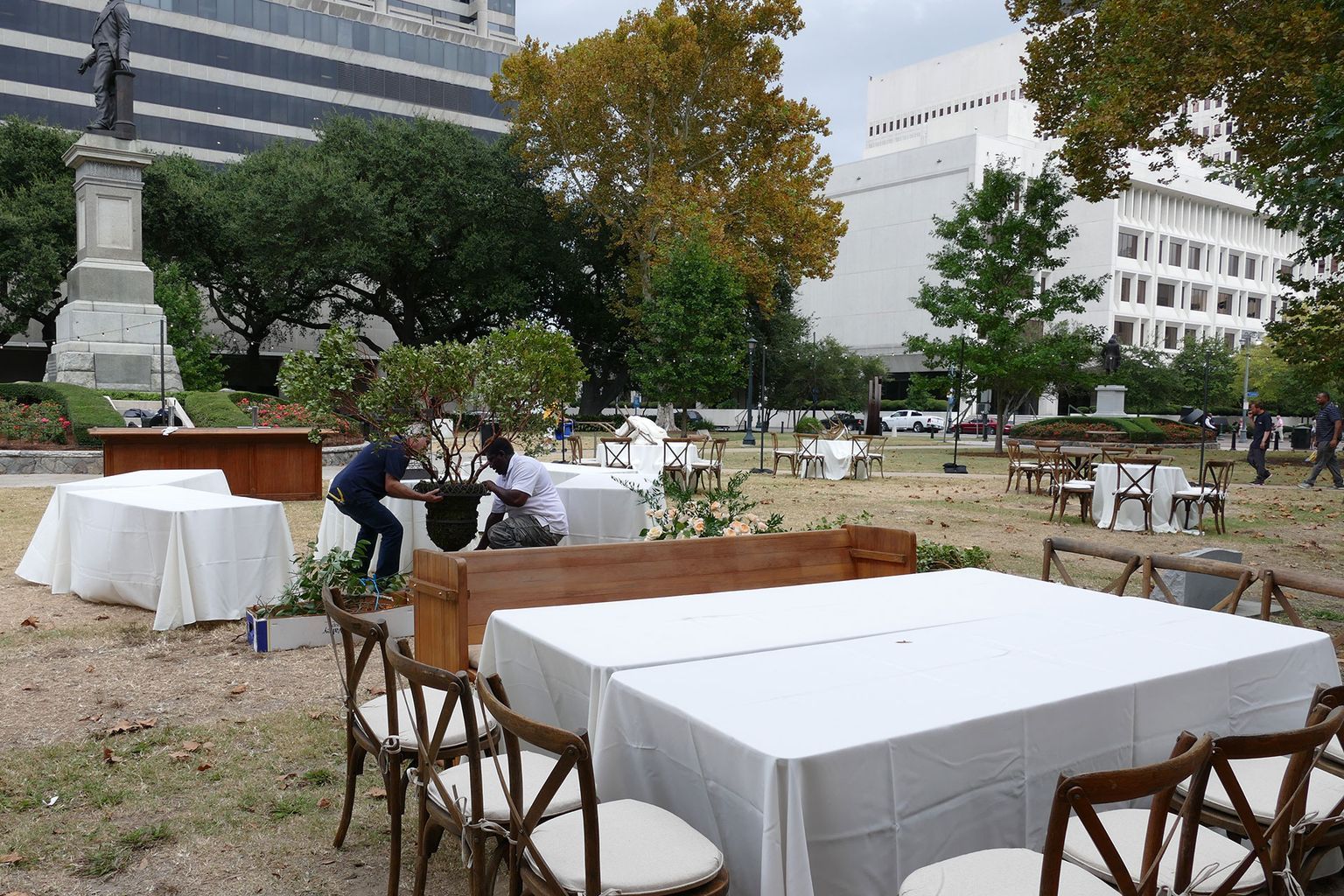 A group of people are setting up tables and chairs in a park.