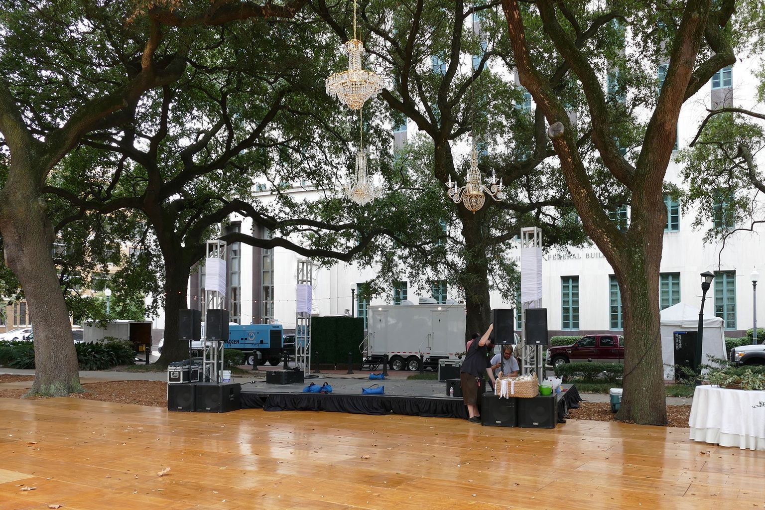 A large wooden dance floor in a park with trees in the background