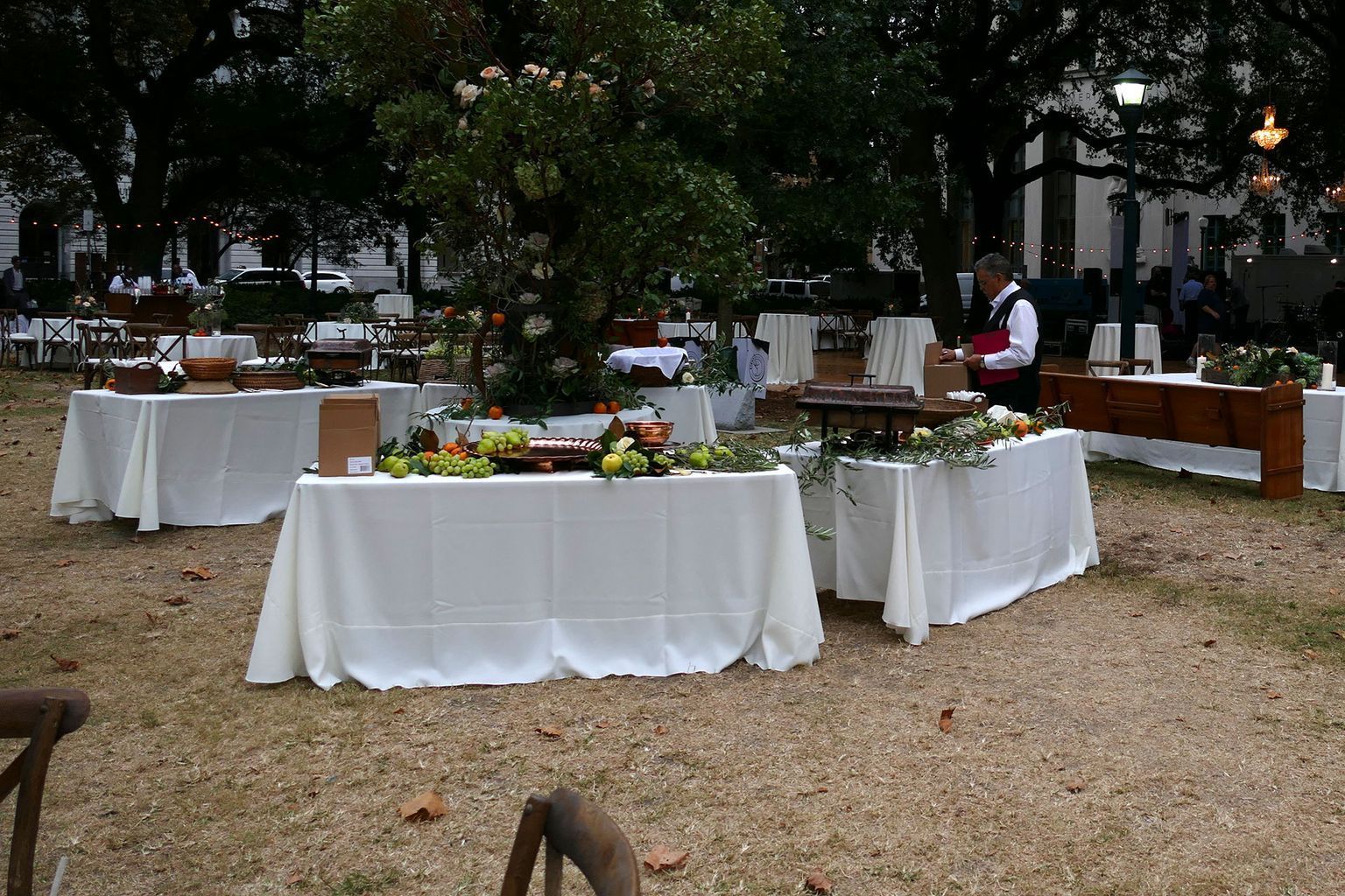 A man in a red vest stands behind a row of white tables