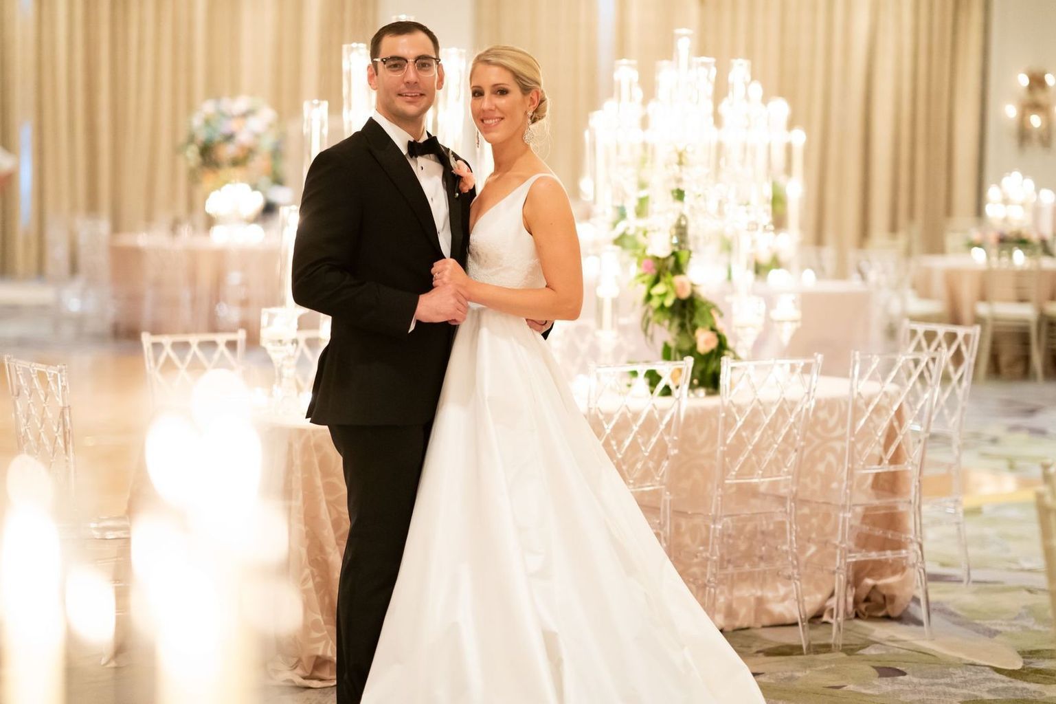 A bride and groom are posing for a picture in a ballroom.