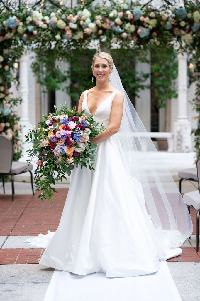 A bride in a wedding dress is holding a bouquet of flowers.