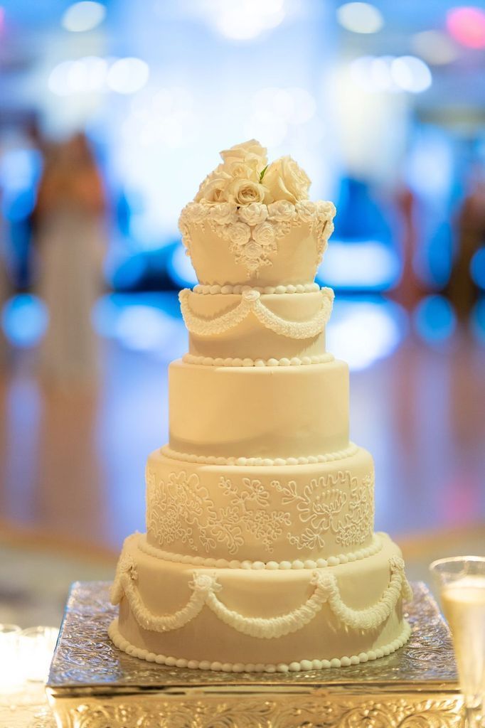 A white wedding cake is sitting on top of a silver plate on a table.