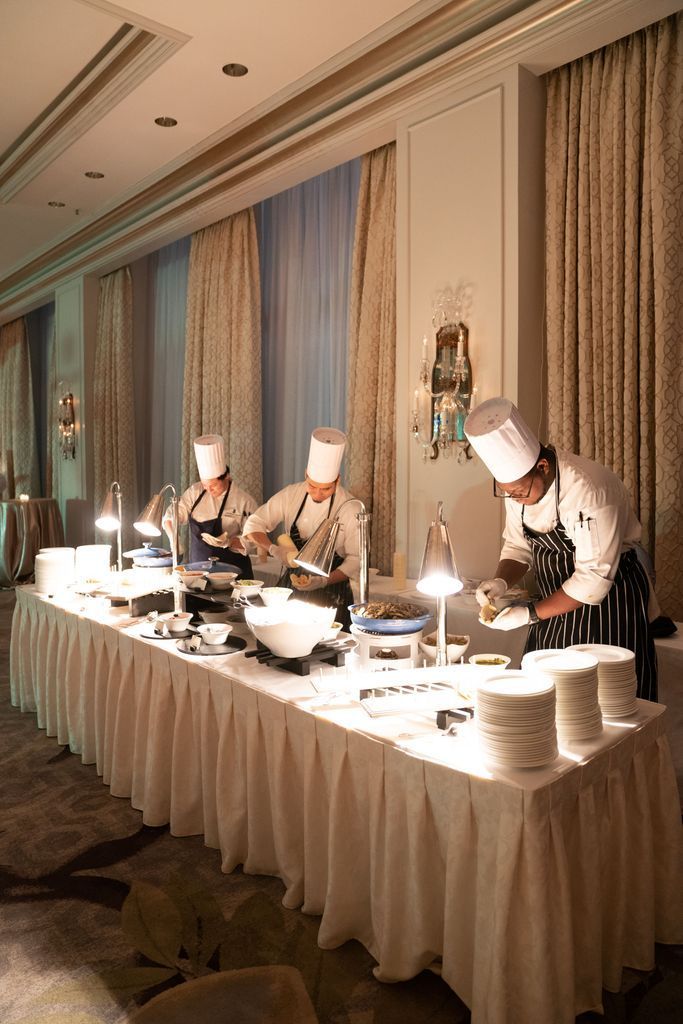 A group of chefs are preparing food at a long table.