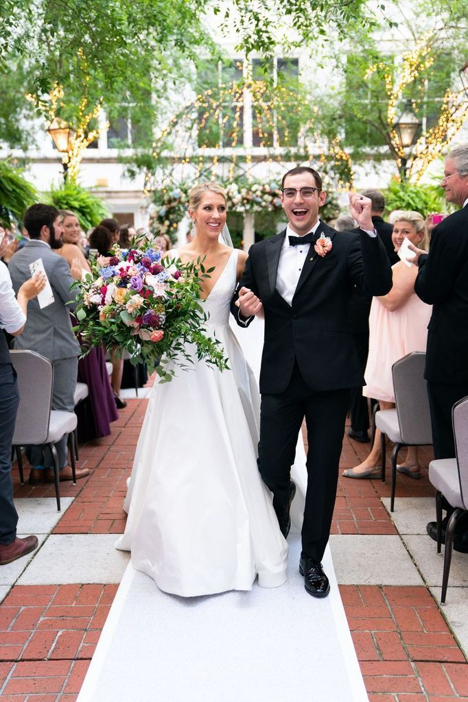 A bride and groom are walking down the aisle at their wedding.