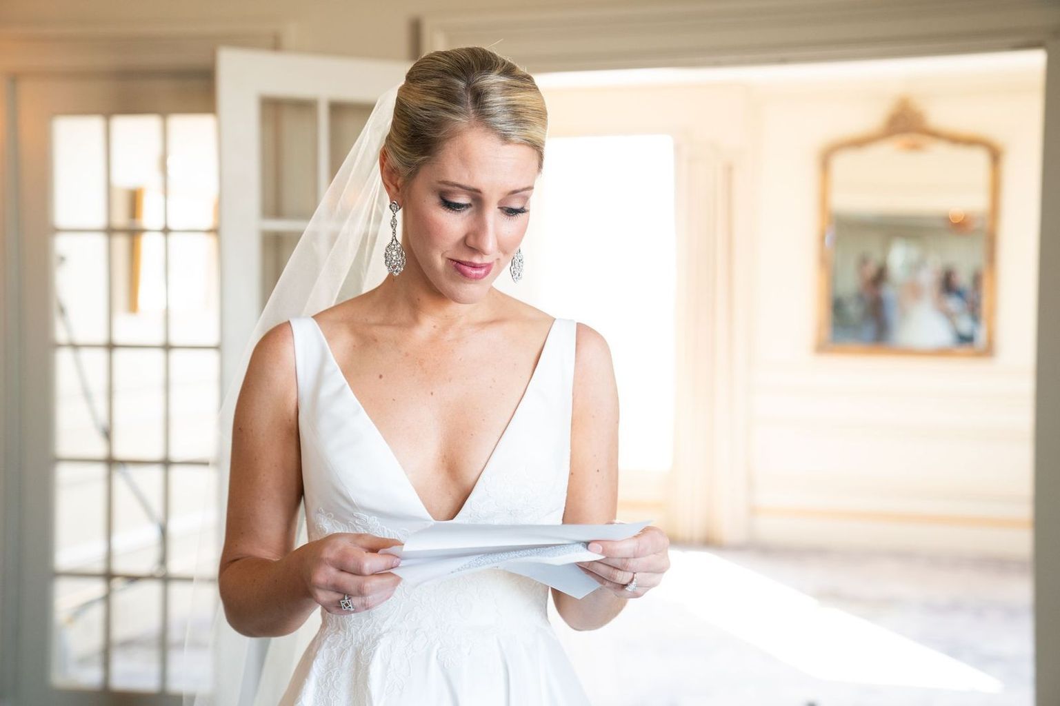 A bride in a wedding dress is reading a letter from her groom.