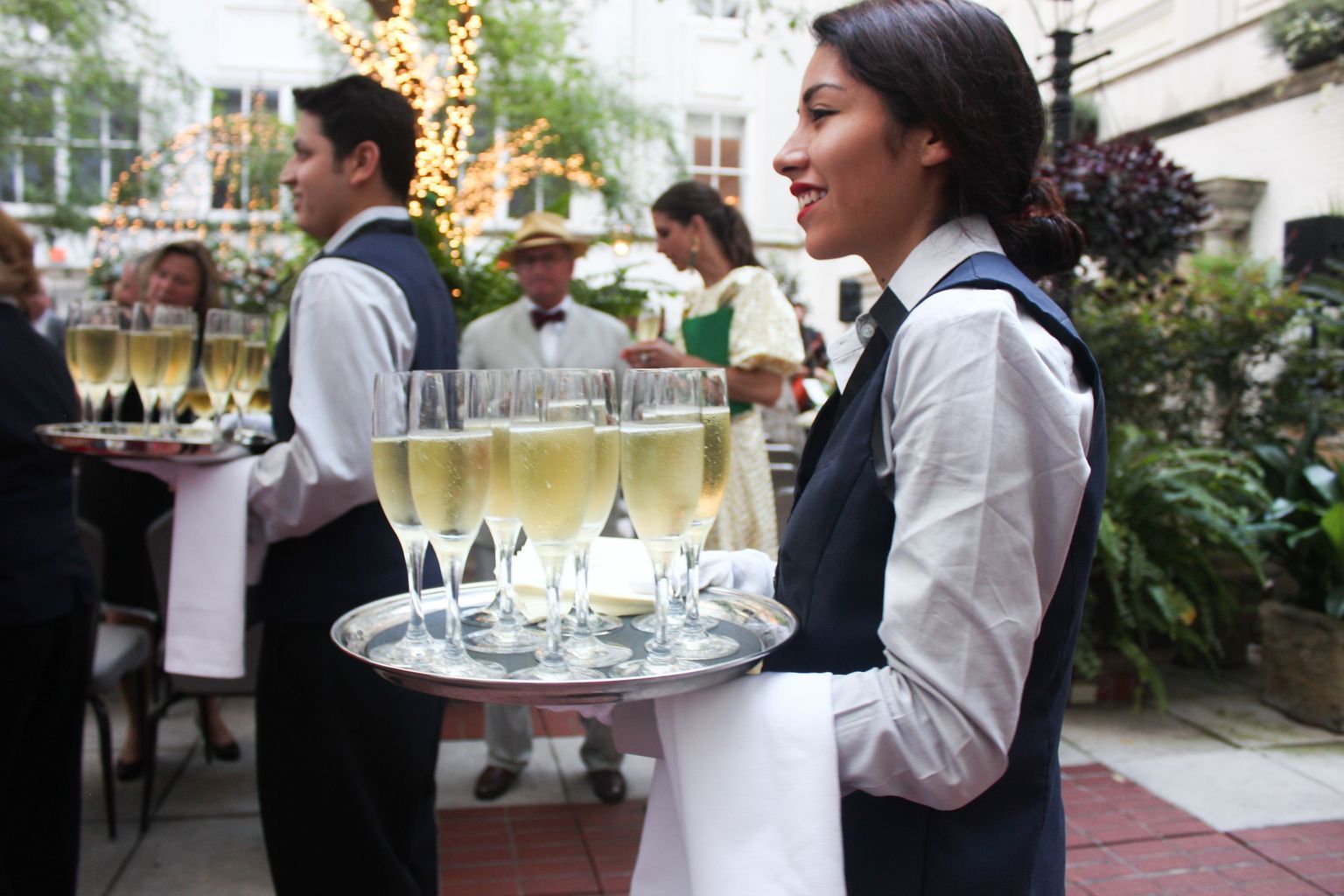 A woman is carrying a tray of champagne glasses