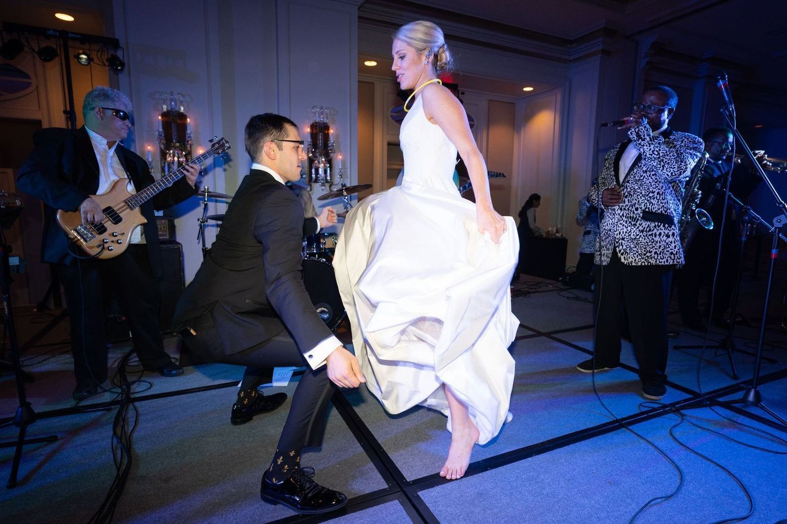 A bride and groom are dancing on a dance floor in front of a band.