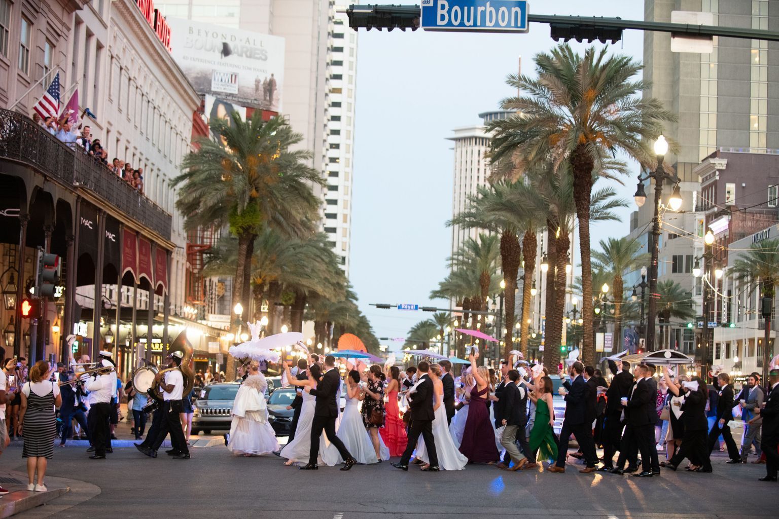 A group of people are crossing a street under a bourbon street sign