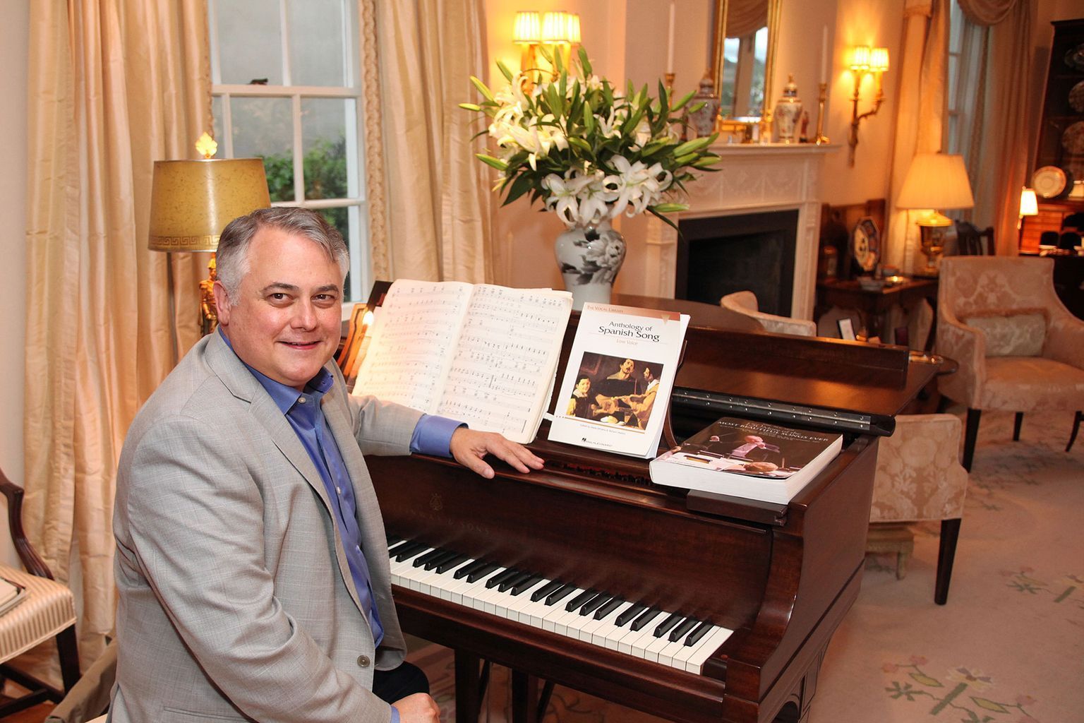 A man is sitting at a piano holding a book