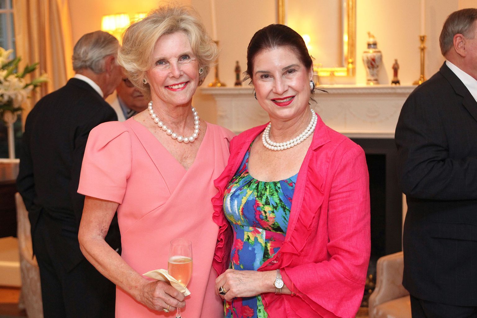 Two women are posing for a picture while holding glasses of champagne.