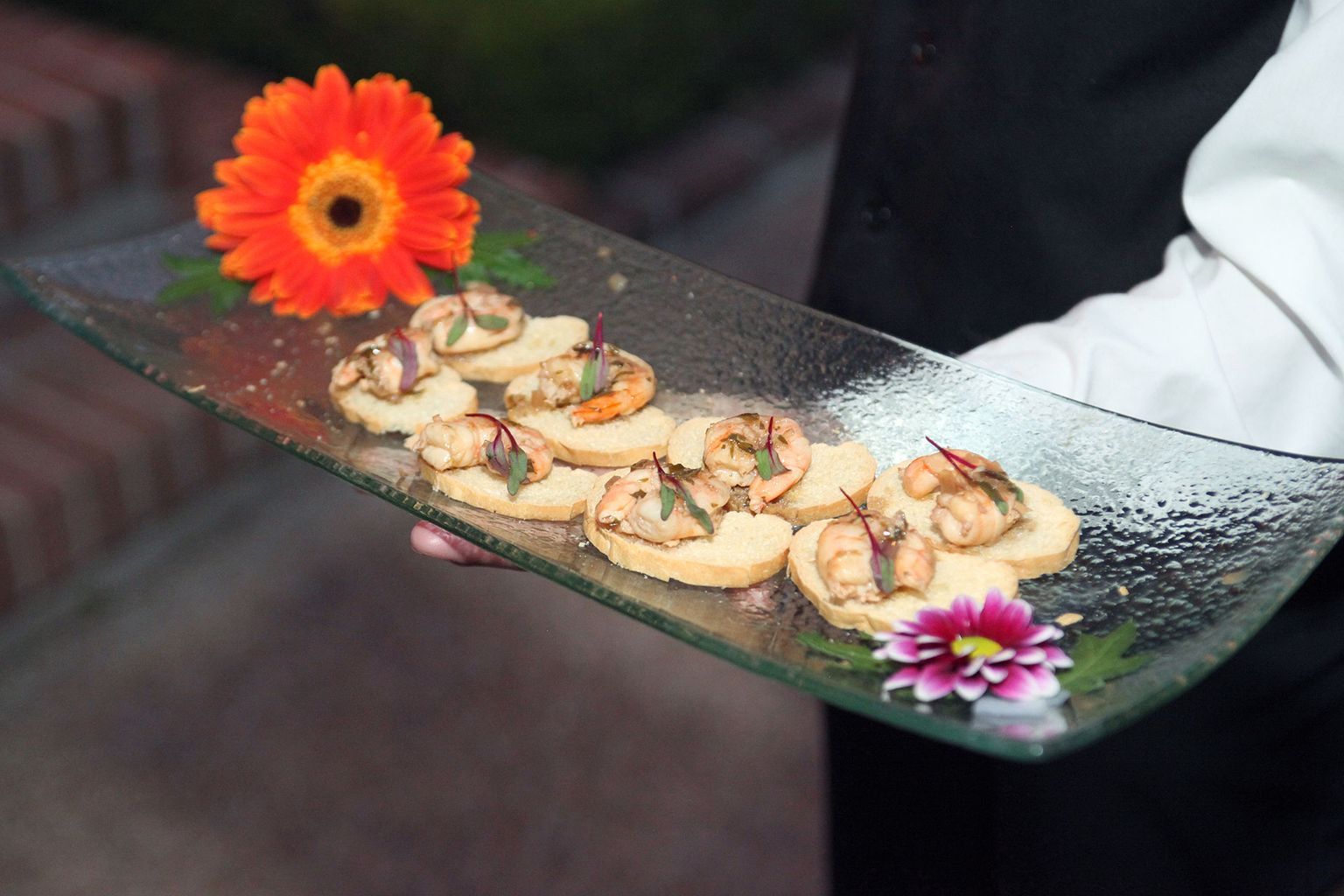 A person is holding a plate of food with a flower on it.