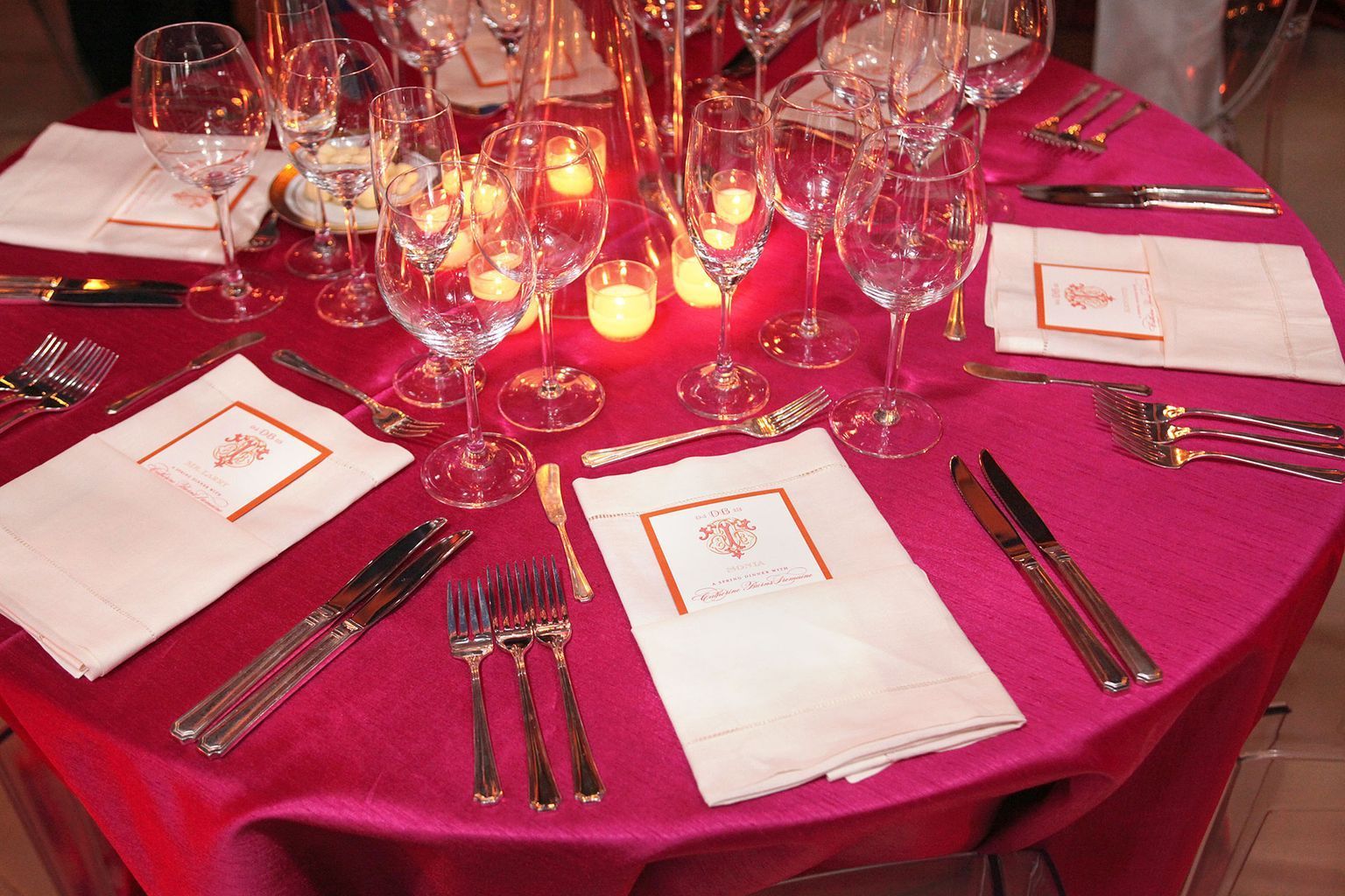 A table set for a dinner party with a pink table cloth