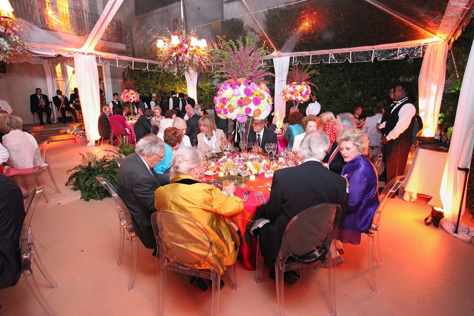 A group of people are sitting at a table under a clear tent.