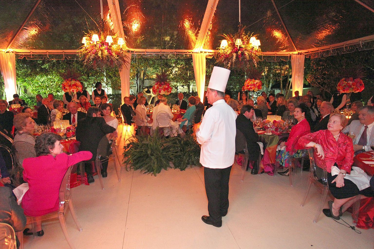 A chef is standing in front of a crowd of people at a party
