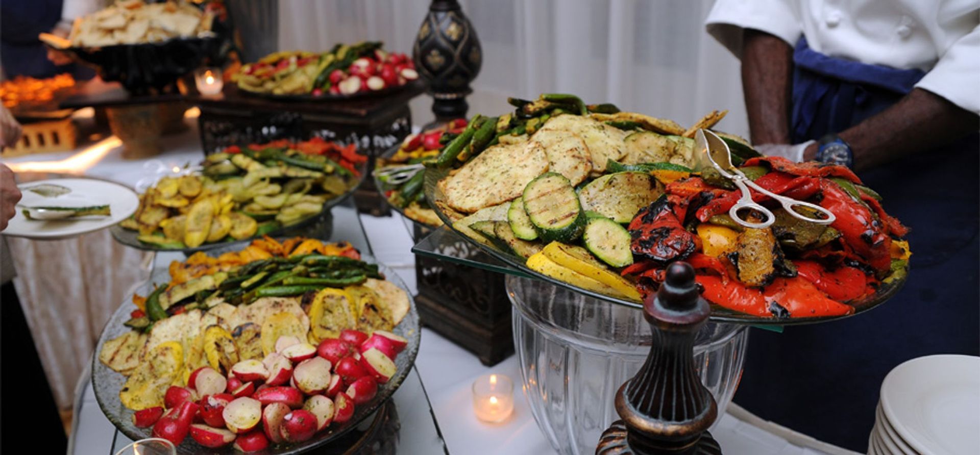A buffet table with a variety of vegetables on it.