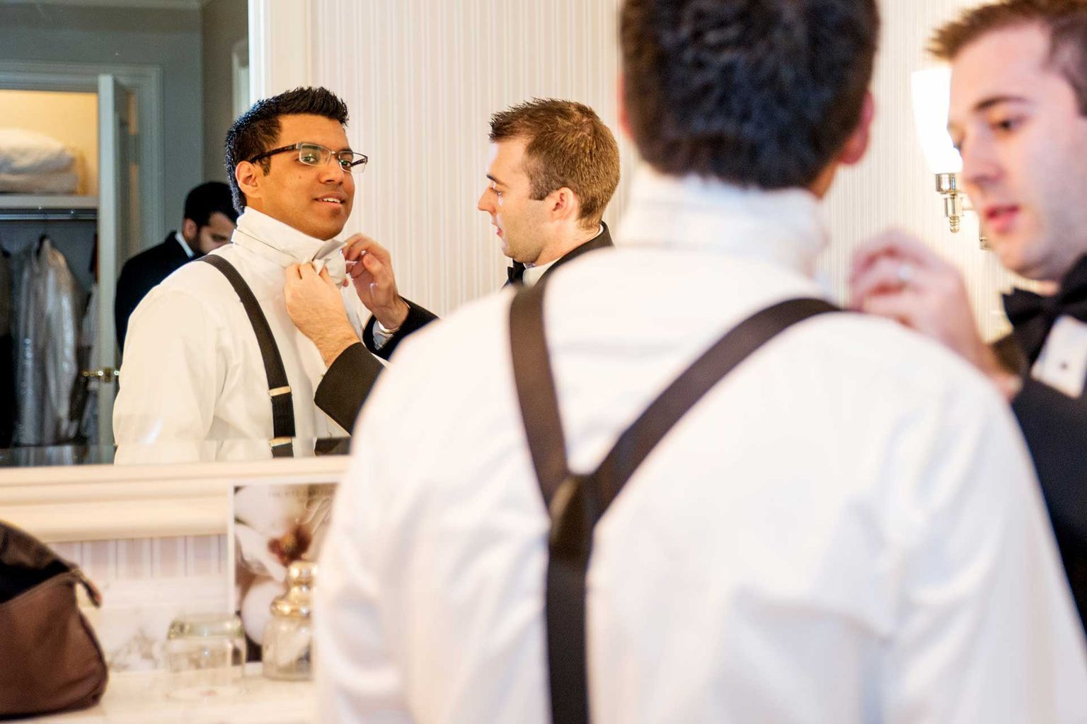 A man is adjusting his tie in front of a mirror.